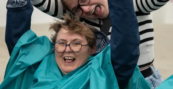Une vacancière et une volontaire se tiennent les mains en souriant