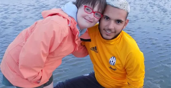 une vacancière et un volontaire sourient sur la plage