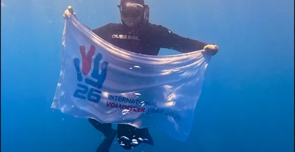 Drapeau tenu par un plongeur "2026, année internationale du volontariat"