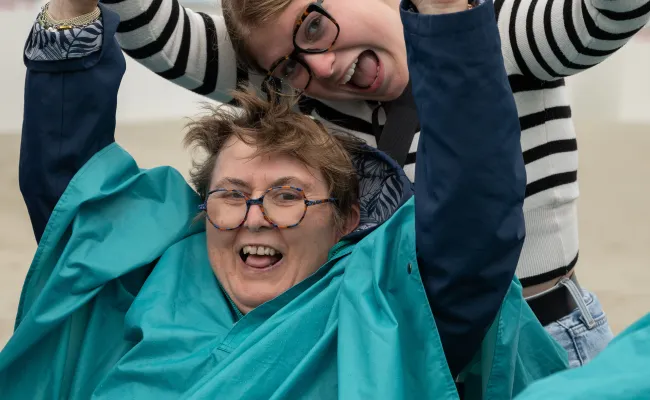 Une vacancière et une volontaire se tiennent les mains en souriant