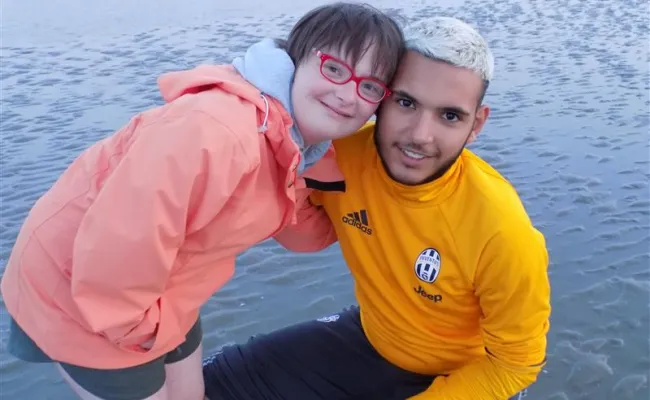 une vacancière et un volontaire sourient sur la plage