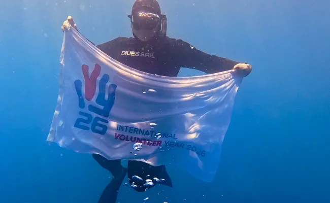 Drapeau tenu par un plongeur "2026, année internationale du volontariat"