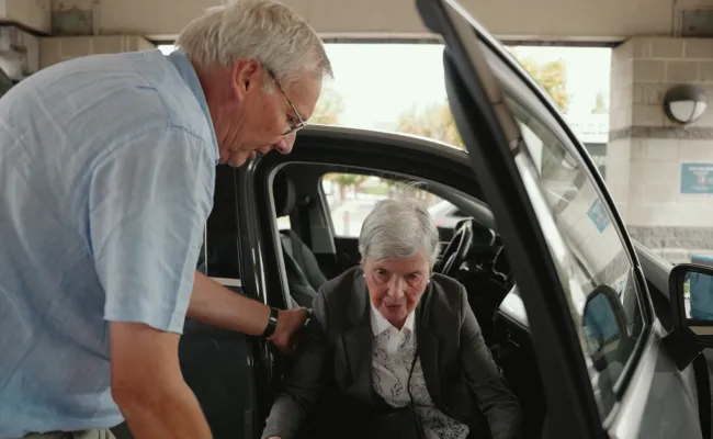 Un volontaire chauffeur aide une personne âgée à sortir du véhicule