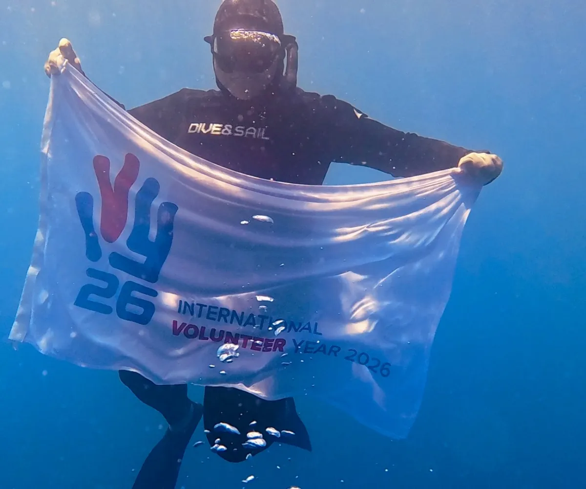 Drapeau tenu par un plongeur "2026, année internationale du volontariat"